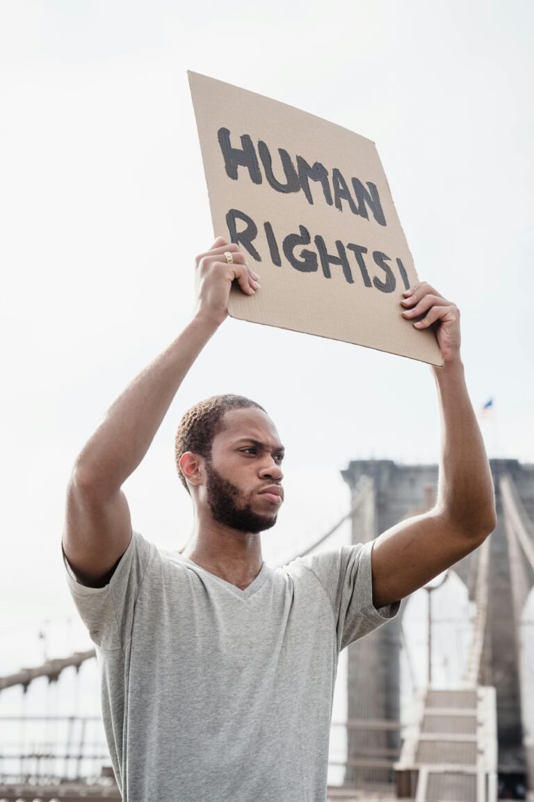 A man stands outdoors holding a 'Human Rights' sign, advocating for equality and justice.